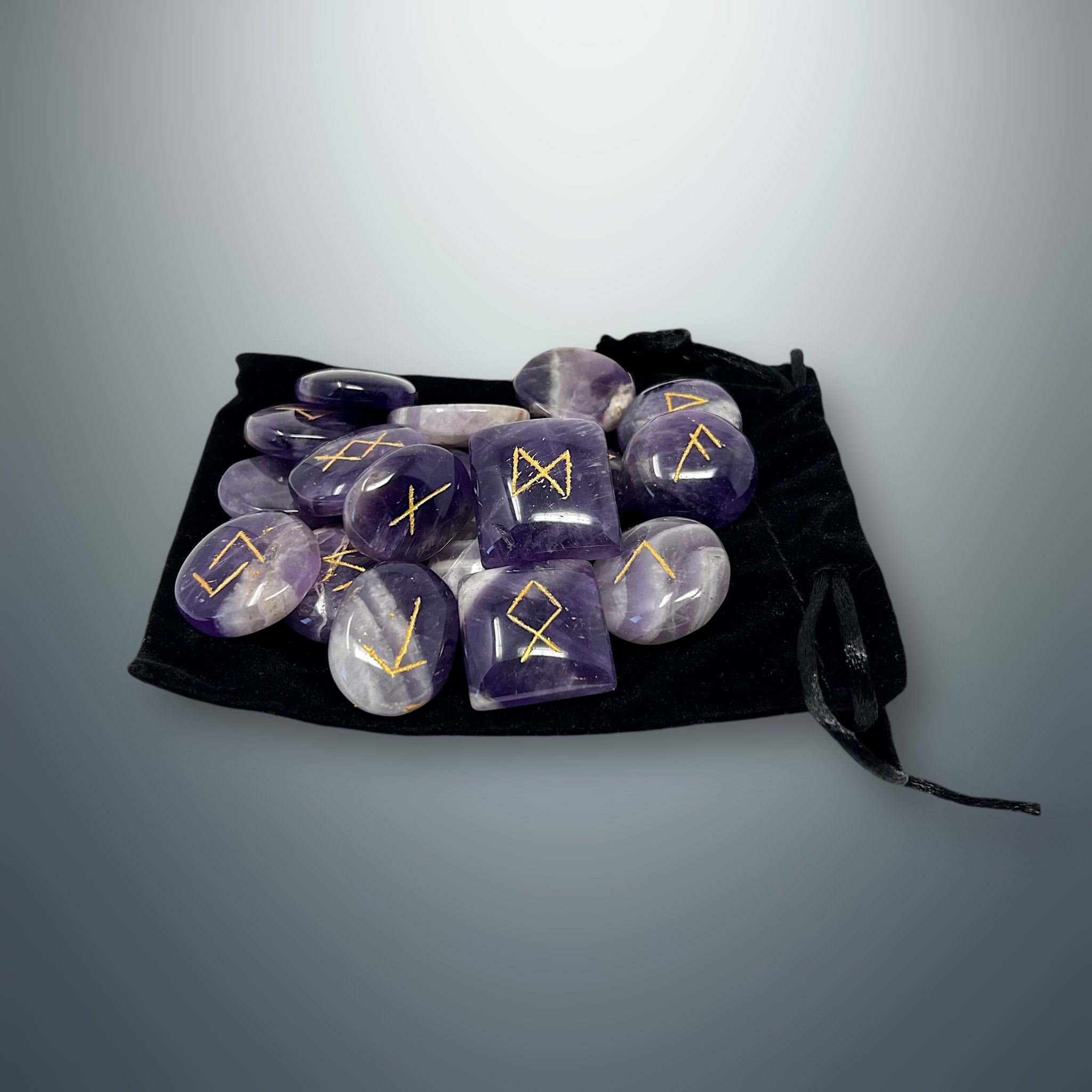 Set de runas de amatista morada sobre una bolsa pequeña de terciopelo negro.