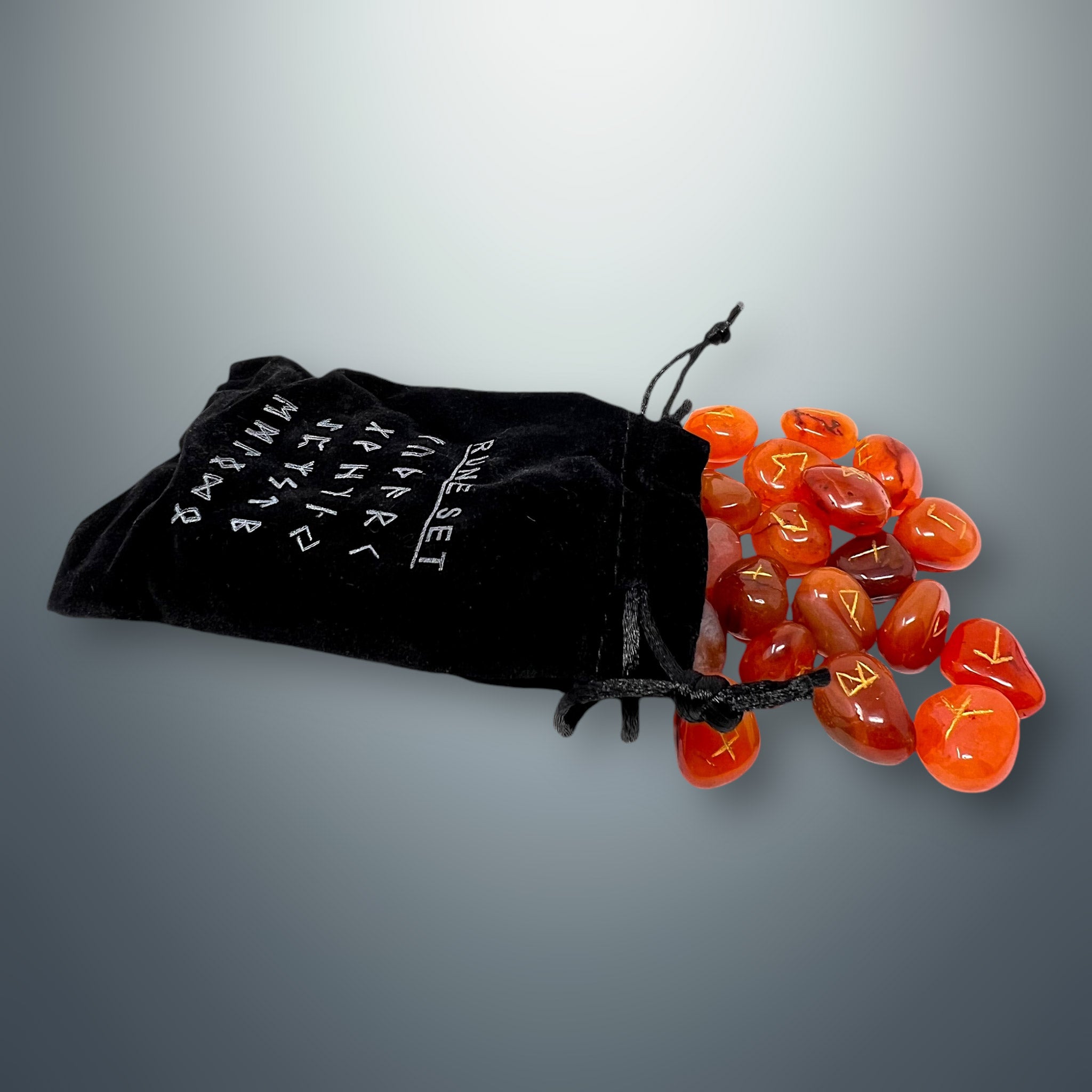 Bolsa pequeña de terciopelo negra con inscripciones rúnicas, de la cual salen algunas runas de cornalina.