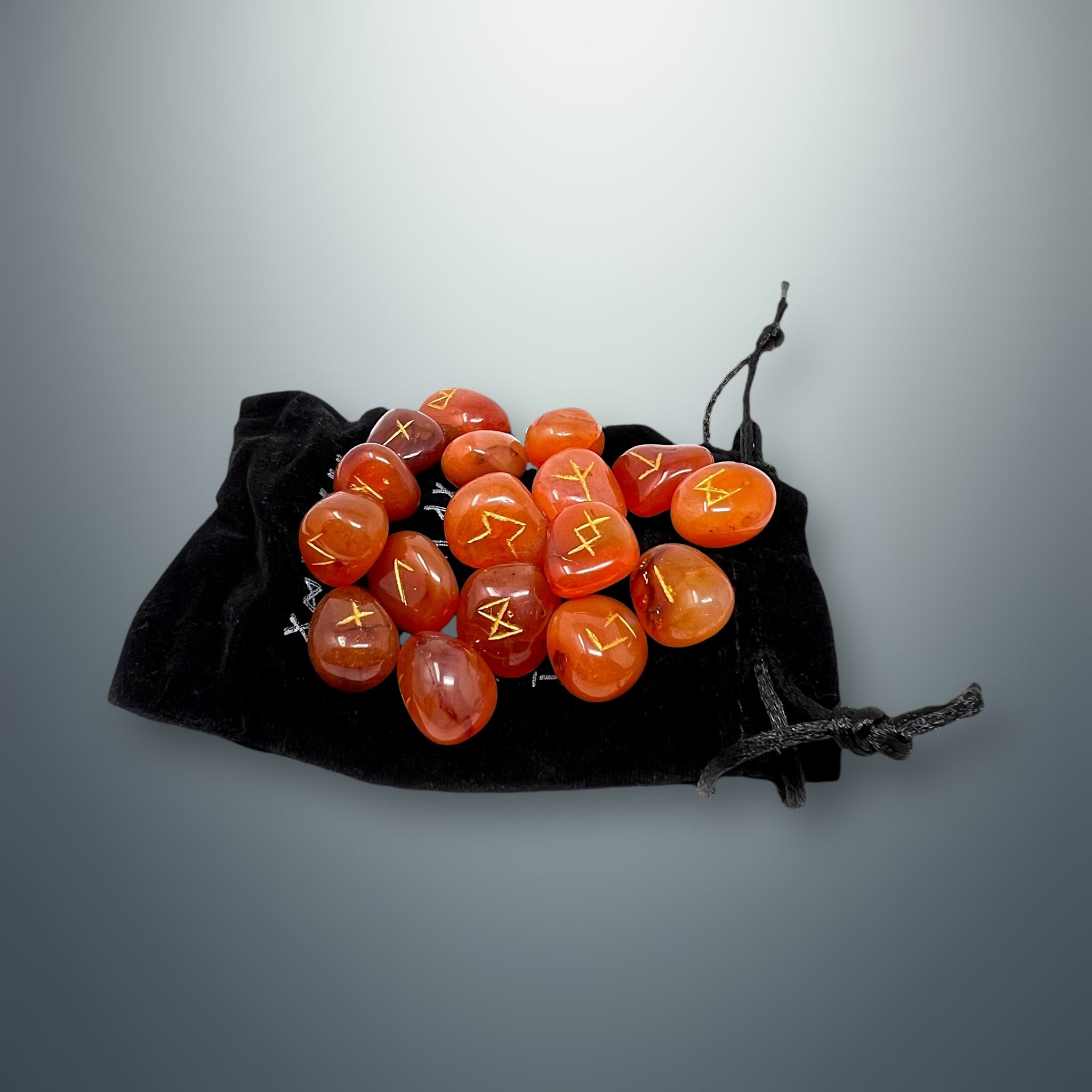 Set de runas de cornalina sobre una bolsa pequeña de terciopelo negro.