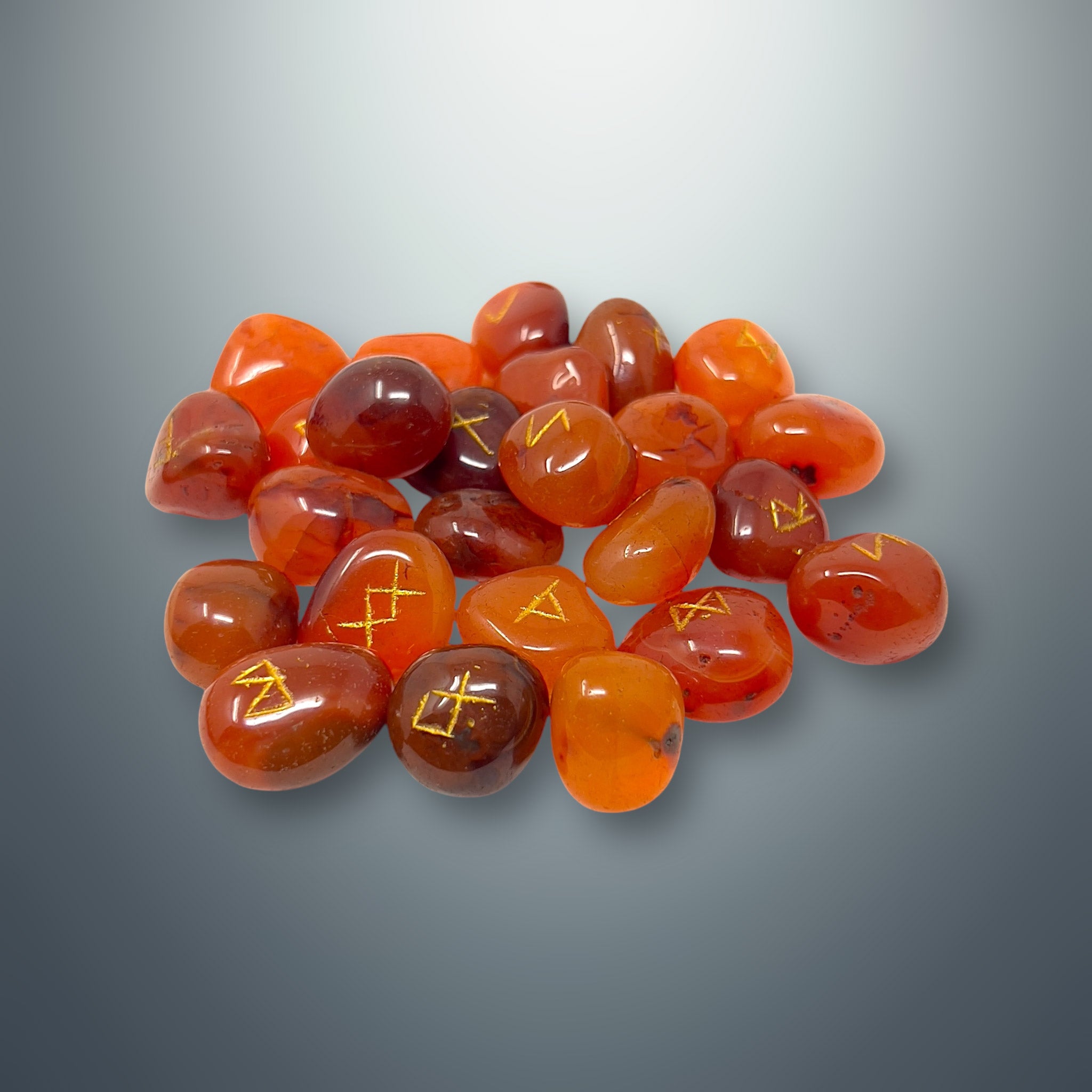 Set de runas de cornalina con los símbolos rúnicos grabados en color dorado.