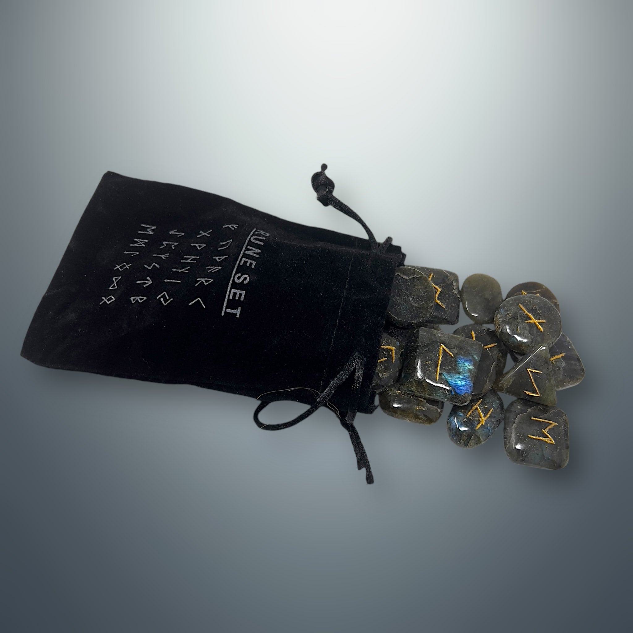 Bolsa pequeña de terciopelo negra con inscripciones rúnicas, de la cual salen algunas runas de labradorita.