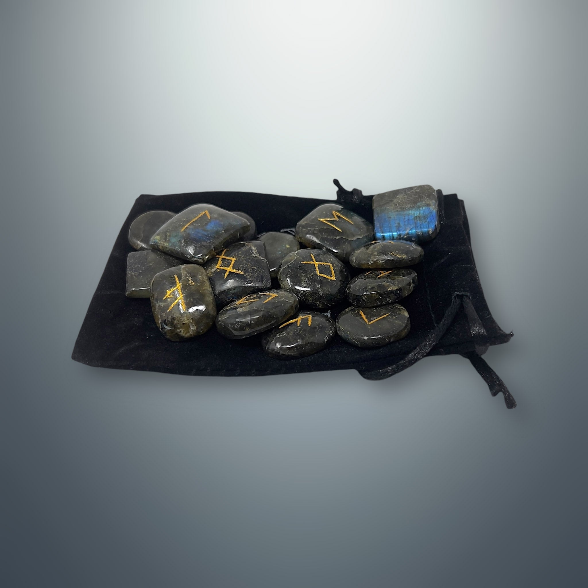 Set de runas de labradorita sobre una bolsa pequeña de terciopelo negro.