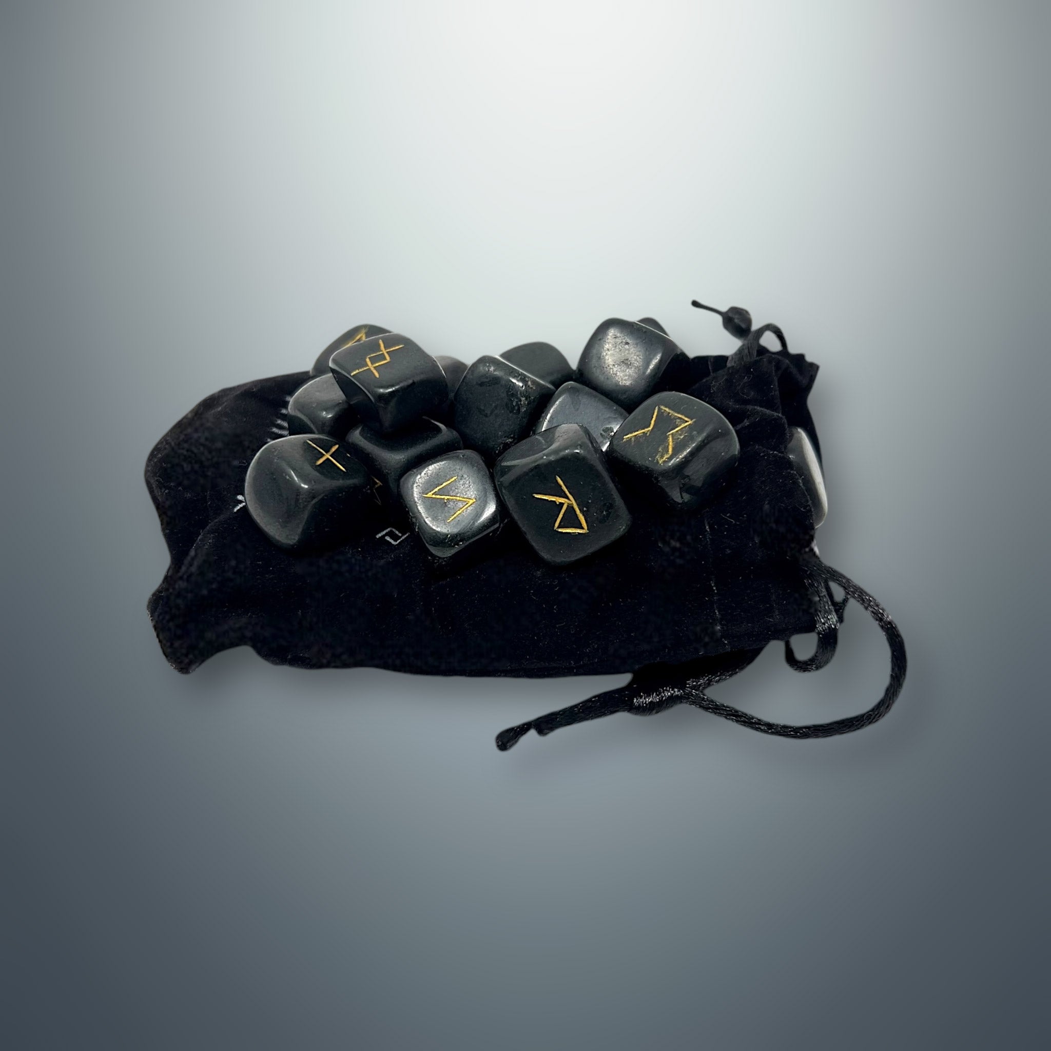 Set de runas de turmalina negra sobre una bolsa pequeña de terciopelo negro.