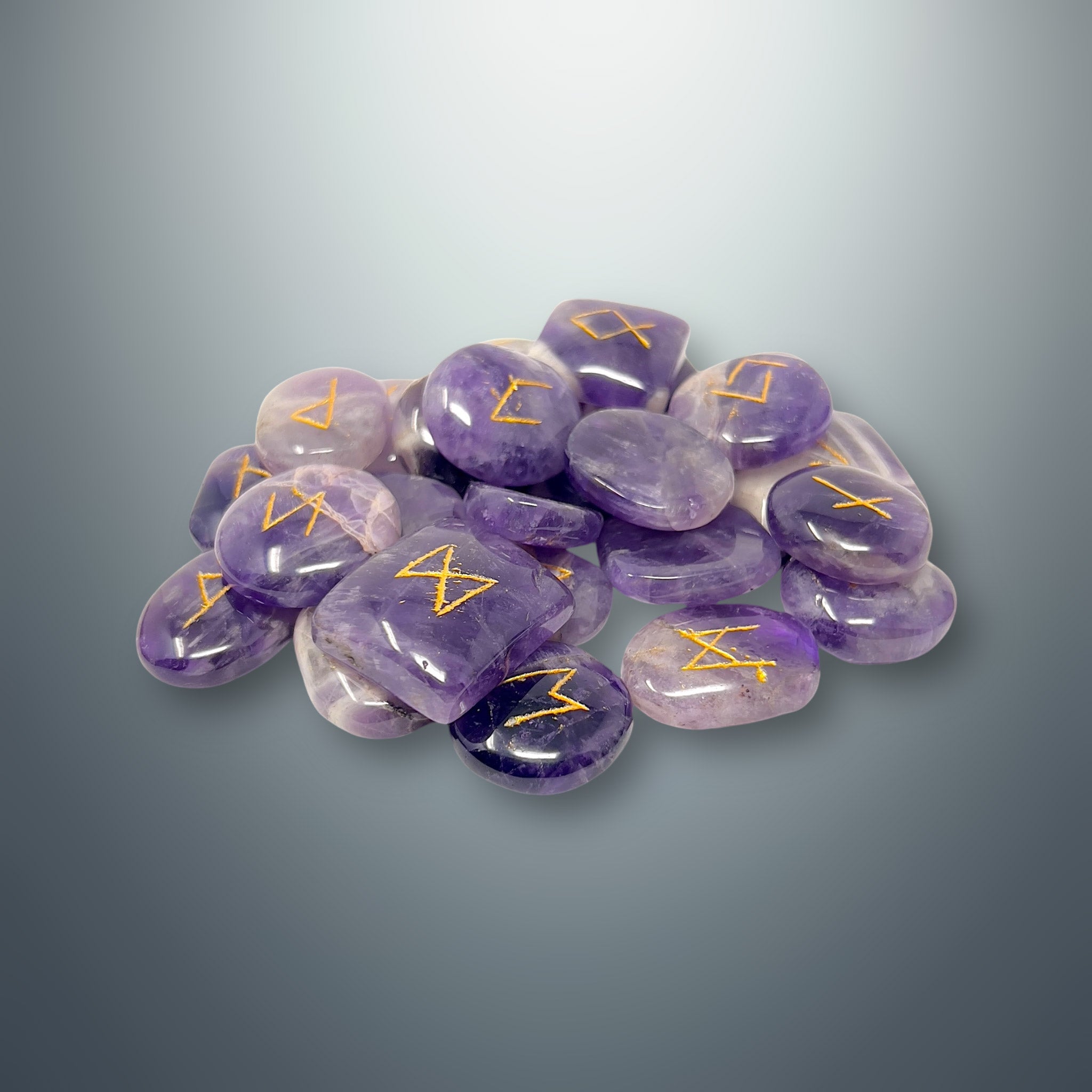 Set de runas de amatista morada con los símbolos rúnicos grabados en color dorado.