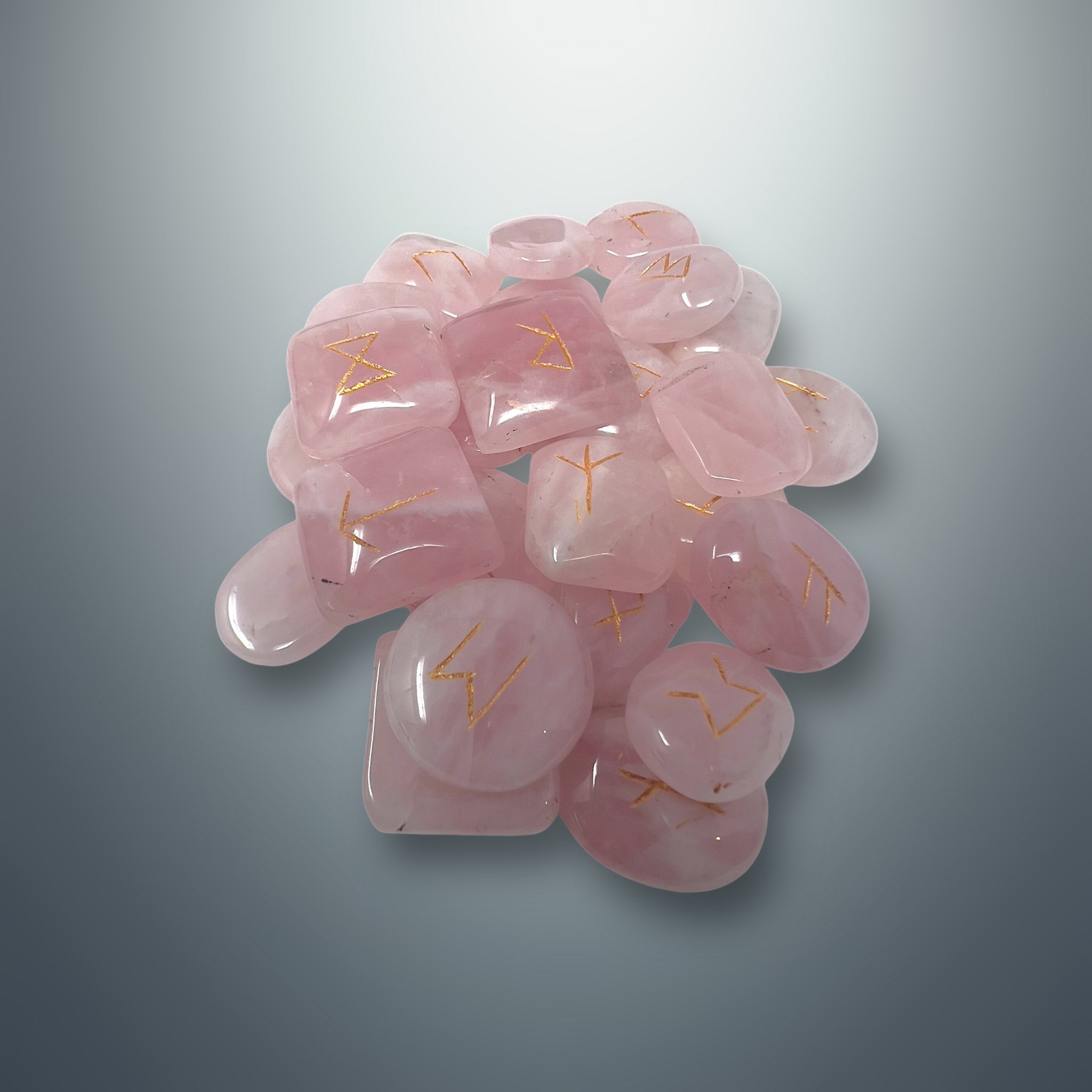 Set de runas de cuarzo rosa con los símbolos rúnicos grabados en color dorado.